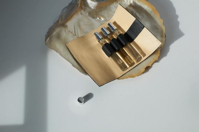 Stylish perfume sample bottles in a leather case on a seashell, showcasing elegance on a white surface.